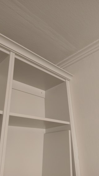 platsbyggd grå bokhylla med bänkskåp måttanpassad mot väggar och tak